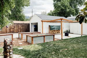 View of yard featuring a vegetable garden, a patio area, and an outbuilding