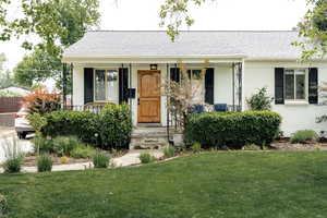View of front of house with a shingled roof, a front lawn, covered porch, stucco siding, and central AC