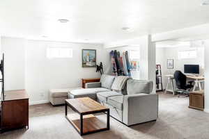 Living room featuring carpet floors, a desk, plenty of natural light, and baseboards