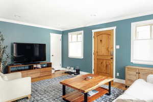 Living room with wood finished floors, crown molding, baseboards, and recessed lighting