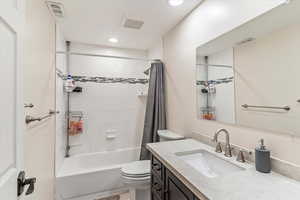 Full bath with vanity, toilet, shower / bath combo with shower curtain, and recessed lighting