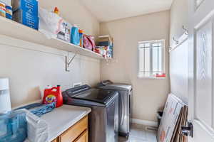 Laundry room featuring washing machine and dryer, light tile patterned floors, and baseboards