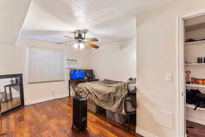 Bedroom featuring dark wood-style flooring, a textured ceiling, ceiling fan, baseboards, and radiator