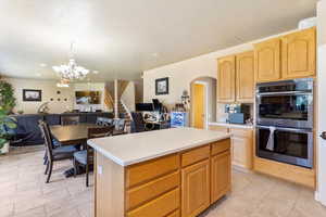 Kitchen with double oven, arched walkways, open floor plan, a chandelier, and light brown cabinetry