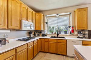 Kitchen featuring white appliances, a sink, light countertops, and light tile patterned floors