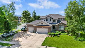 View of front facade featuring an attached garage, driveway, brick siding, and a shingled roof