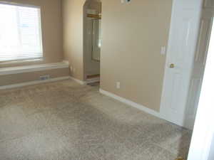 Carpeted spare room with arched walkways and baseboards