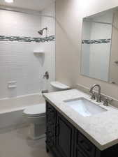 Bathroom with vanity, toilet, shower / bath combination, and tile patterned floors