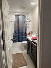 Full bathroom featuring shower / tub combo with curtain, toilet, tile patterned floors, vanity, and recessed lighting