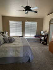 Bedroom with carpet, a ceiling fan, a textured ceiling, and arched walkways
