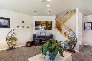 Living area with carpet flooring, stairway, a textured ceiling, and baseboards