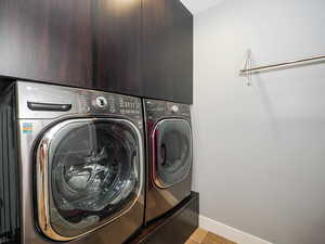 Laundry room with washing machine and clothes dryer, baseboards, and light wood-style flooring