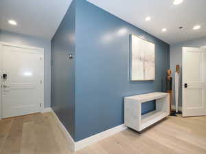 Hall with light wood-style floors, recessed lighting, and baseboards