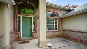 View of exterior entry featuring brick siding and stucco siding