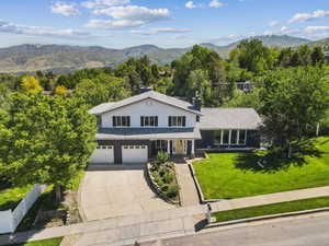 View of front of property featuring concrete driveway, a garage, a mountain view, and a chimney