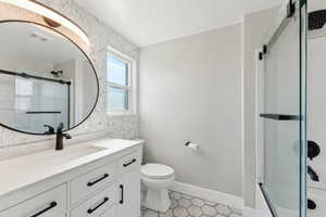 Bathroom with vanity, toilet, tile patterned flooring, and enclosed tub / shower combo