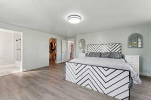 Bedroom with a spacious closet, light wood-style flooring, baseboards, and a closet