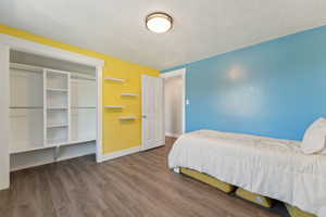 Bedroom featuring baseboards, wood finished floors, a textured ceiling, and a closet