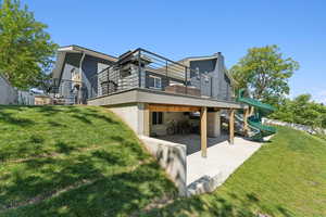 Back of house with a patio, a playground, a lawn, and stucco siding