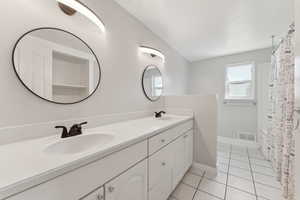 Full bathroom with double vanity, tile patterned flooring, and baseboards