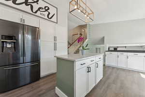 Kitchen with stainless steel fridge, light wood-style floors, and white cabinets