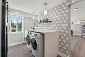 Laundry area featuring separate washer and dryer, baseboards, light wood-type flooring, recessed lighting, and an accent wall