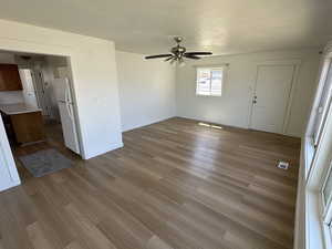Unfurnished living room featuring wood finished floors, a ceiling fan, and baseboards