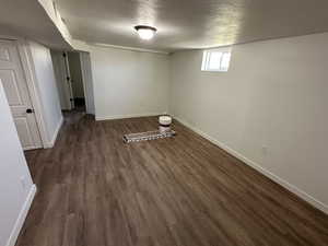 Below grade area with dark wood finished floors, a textured ceiling, and baseboards