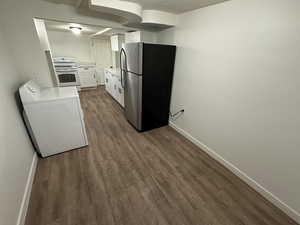 Kitchen featuring electric stove, freestanding refrigerator, washer / clothes dryer, dark wood-style flooring, and baseboards