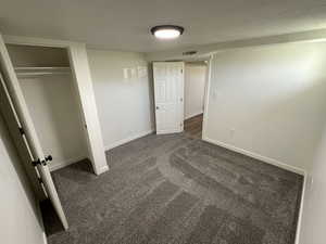 Unfurnished bedroom with dark carpet, baseboards, and a closet