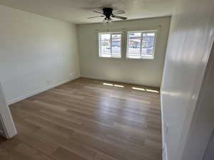 Spare room with ceiling fan, wood finished floors, baseboards, and a textured ceiling