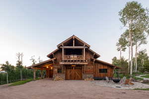 View of front of house with dirt driveway, stone siding, and a barn