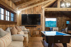 Rec room featuring wood walls, wood-type flooring, wooden ceiling, and a chandelier