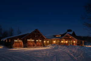 View of front of property with a chimney, dirt driveway, a garage, and stone siding