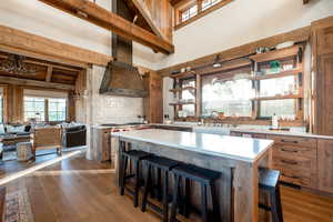 Kitchen featuring a sink, high vaulted ceiling, light countertops, dark wood-type flooring, and a breakfast bar area