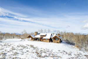 Snow covered rear of property featuring a chimney