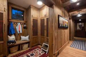 Mudroom with wooden walls, wood finished floors, and beamed ceiling