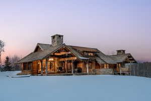 View of front of home featuring a chimney, stone siding, and a patio area