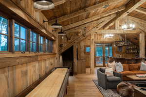 Living room with wooden walls, wood ceiling, a chandelier, hardwood / wood-style floors, and french doors