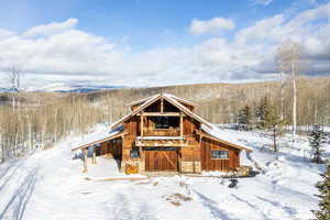 View of front of property with a balcony and a view of trees