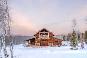 View of front of property featuring a balcony, stone siding, and a barn