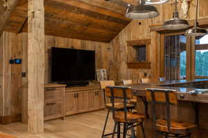 Bar area featuring wooden ceiling, wood walls, light wood-type flooring, and decorative light fixtures