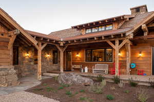 View of exterior entry featuring covered porch and stone siding