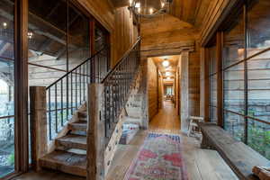 Stairway featuring wooden walls, wood-type flooring, wood ceiling, high vaulted ceiling, and a chandelier