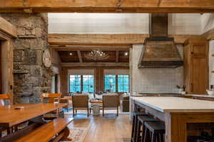 Kitchen featuring custom range hood, beamed ceiling, light wood-style flooring, light countertops, and stainless steel gas stovetop