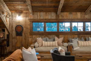 Living area featuring wood ceiling with exposed beams, wooden walls, and wood finished floors