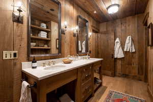 Full bathroom with wood ceiling, wooden walls, hardwood / wood-style floors, and double vanity