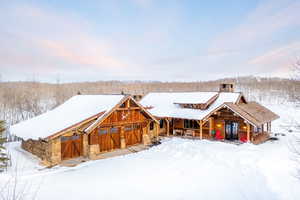 View of front of house with stone siding, a chimney, and a porch