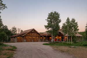 Rustic home featuring driveway, stone siding, and an attached garage