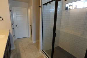 Full bathroom with a shower stall, vanity, and baseboards